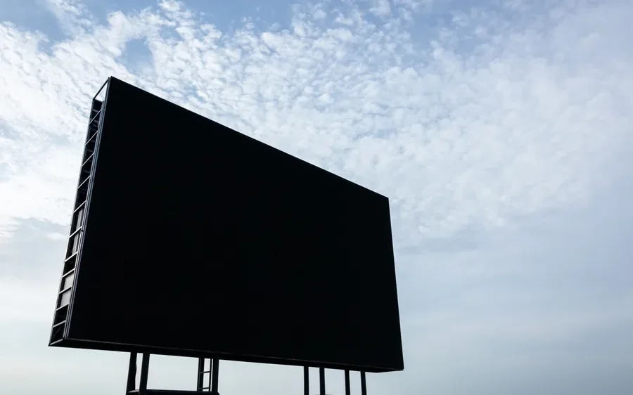 Pantalla LED de gran formato instalada en altura sobre una avenida al atardecer